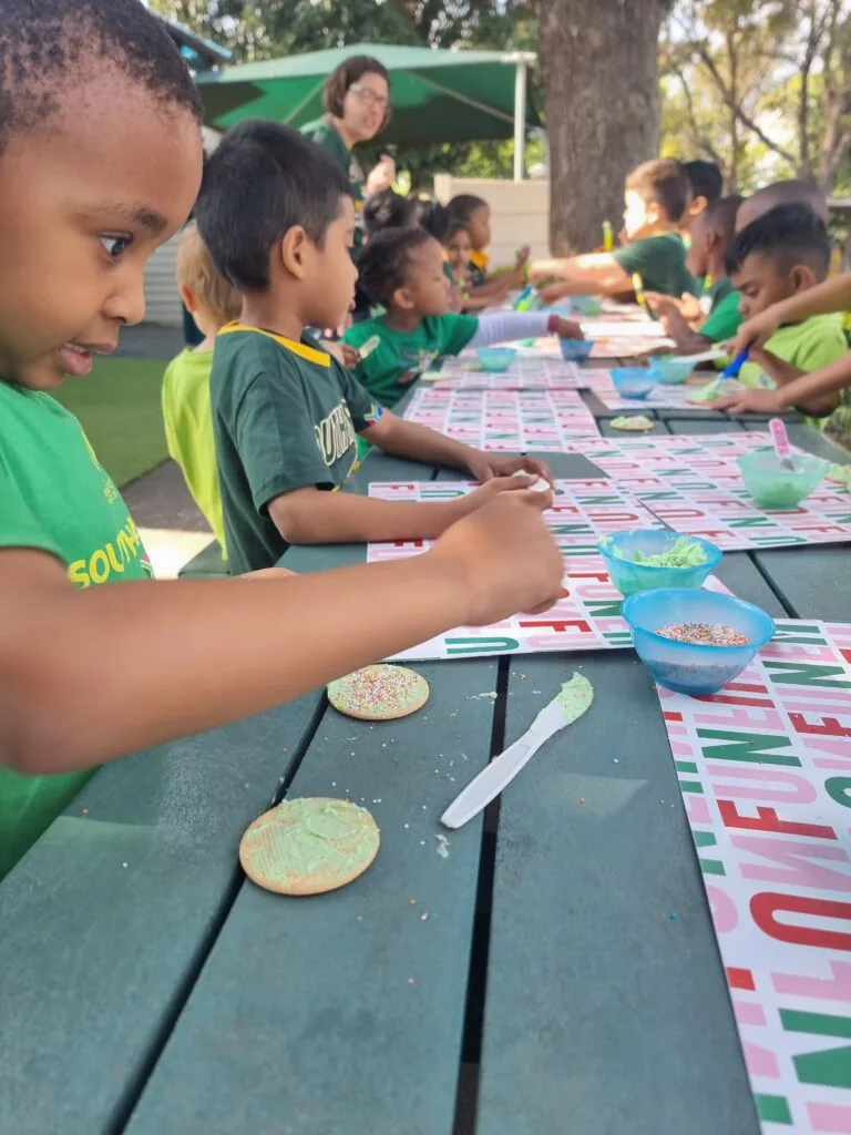 Scamps children decorating biscuits together at the outdoor tables